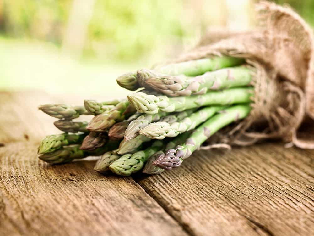a bunch of fresh asparagus on a wooden table