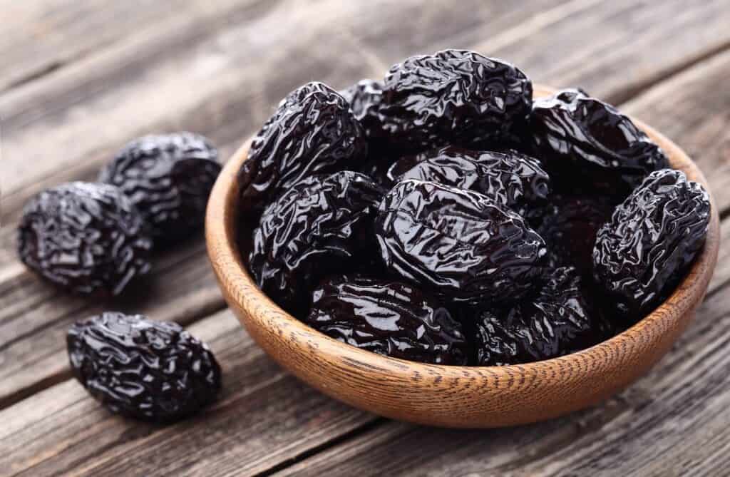 A wooden bowl full of prunes.