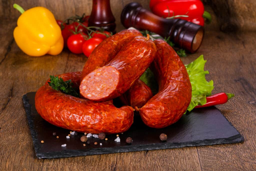 A pile of chorizo on a cutting board with a wooden background.